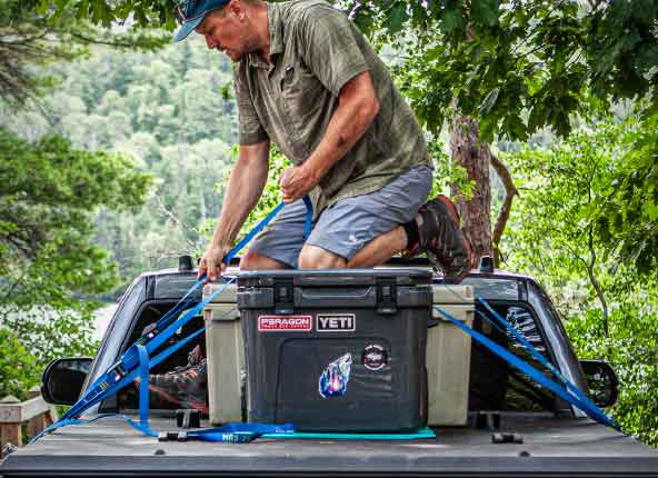 A man strapping coolers to the top of the cover.
