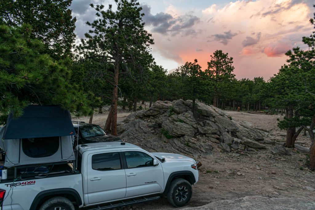 White Toyota Tacoma shown with Peragon truck bed cover, overland rack, and tent.